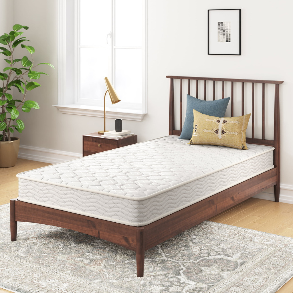 Wood bed frame with a white quilted mattress on a rug